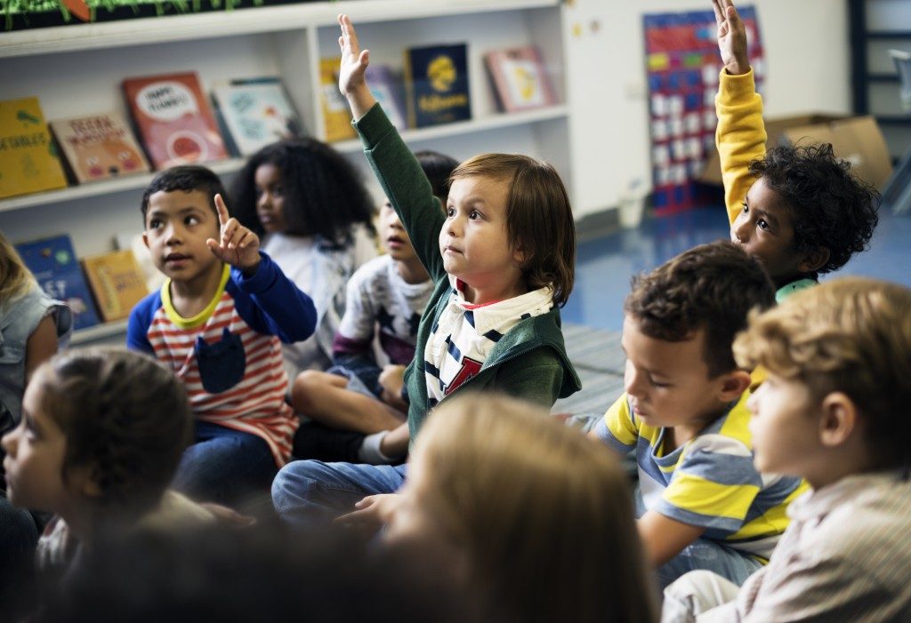children raising their hands in their class