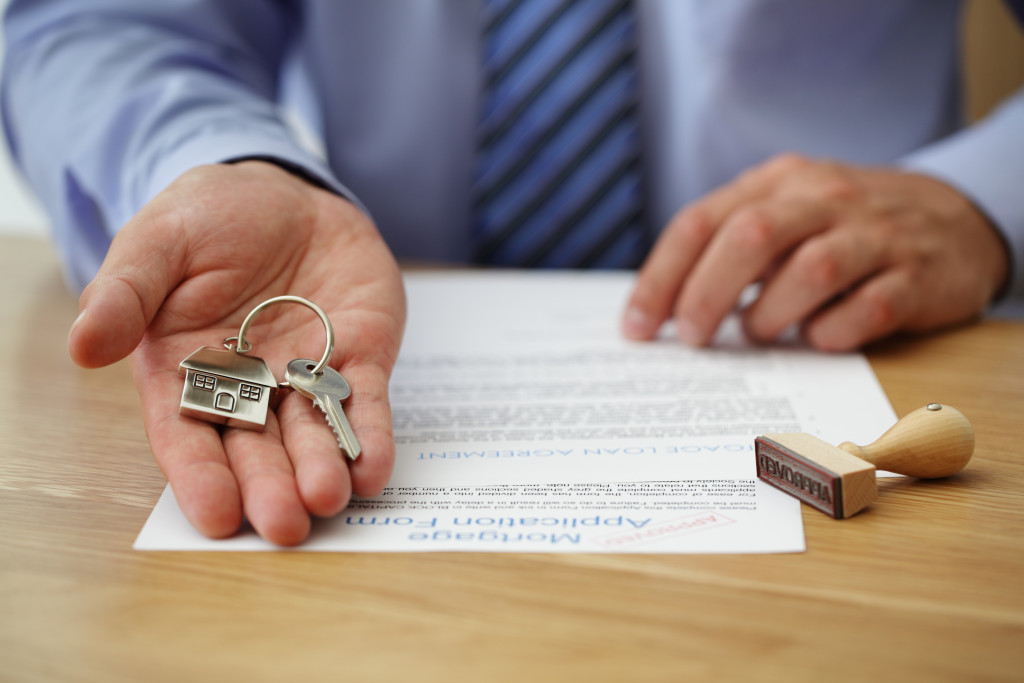 person holding a key and a house title